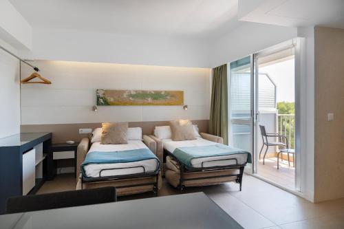 a hotel room with two beds and a balcony at Bordoy Cosmopolitan in Playa de Palma