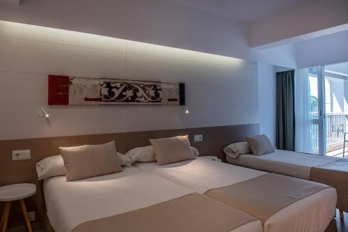 a hotel room with two beds and a window at Bordoy Cosmopolitan in Playa de Palma