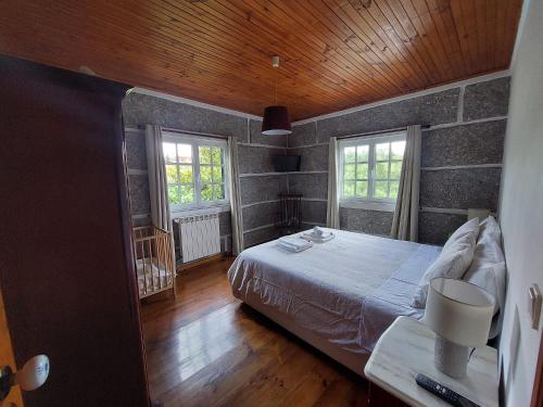a bedroom with a large bed and two windows at Casa da Marcolininha in Vieira do Minho