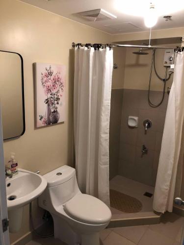 a bathroom with a toilet and a sink and a shower at Majestic One Bedroom Condo Unit in Iloilo City