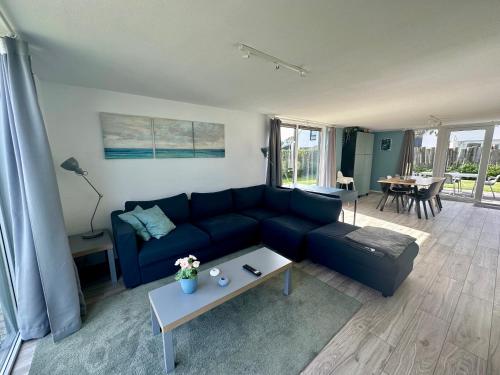 ein Wohnzimmer mit einem blauen Sofa und einem Tisch in der Unterkunft De Wielen 58 in Sint Maarten