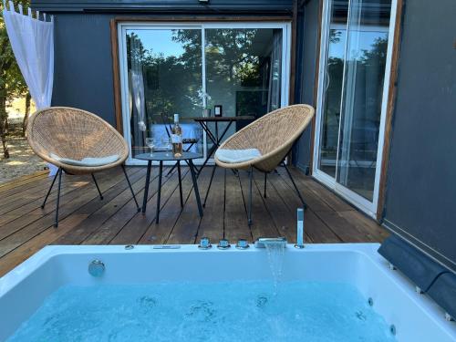 - un bain à remous sur une terrasse avec 2 chaises et une table dans l'établissement Superbe Cabane JACUZZI JARDIN CLIM WIFI PARKING, à Meyreuil