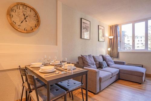 - un salon avec une table et une horloge murale dans l'établissement Apartment Jonquille 2C - Chamonix Peaks Getaway, à Chamonix-Mont-Blanc