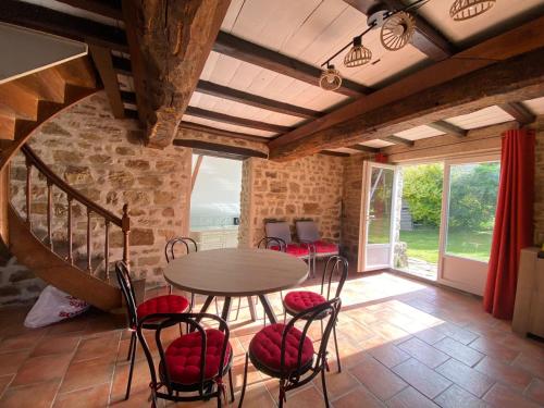 a dining room with a table and chairs and a staircase at Gîte des Rochers in Lonlay-lʼAbbaye