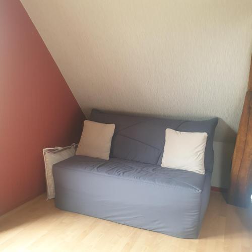 a blue couch with two pillows sitting in a room at Gîte des Rochers in Lonlay-lʼAbbaye