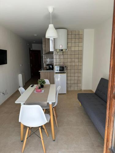 a kitchen and living room with a table and a couch at Apartamentos Peñaflor in Guadix