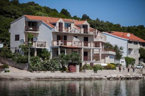 a large building next to a body of water at Apartments Malo Lago in Lastovo