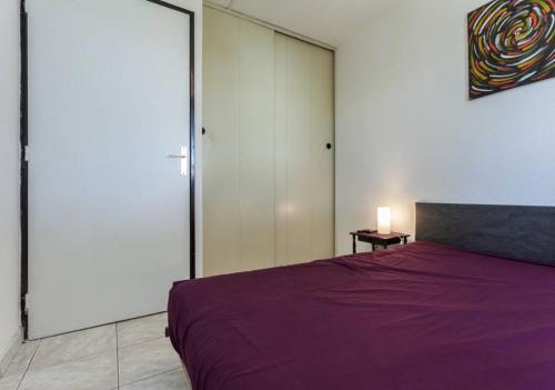 - une chambre avec un lit violet et une porte coulissante dans l'établissement Bel appartement avec balcon, au Cap d'Agde