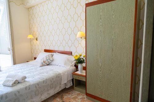 a bedroom with a bed and a table with flowers on it at Hotel Villa Tiziana in Marina di Pietrasanta