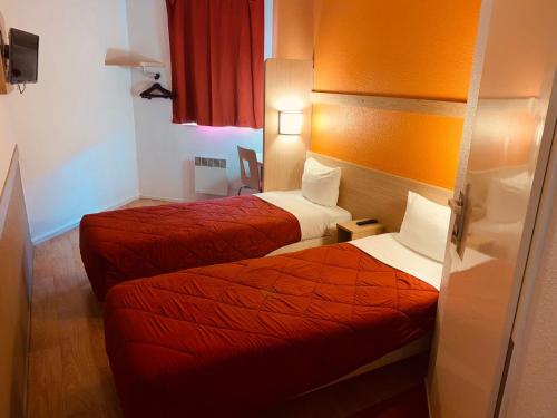 two beds in a hotel room with red sheets at Premiere Classe Roissy CDG - Paris Nord 2 - Parc des Expositions in Roissy-en-France