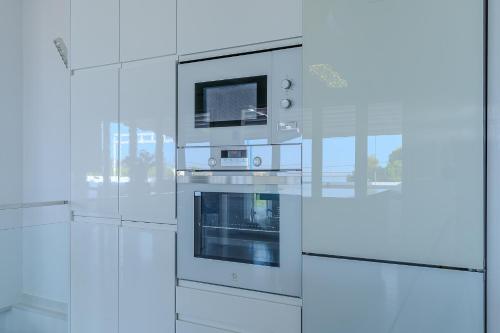 a kitchen with white cabinets and an oven at Casa Mazagón con vistas al mar in Mazagón