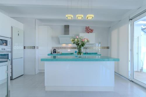 a white kitchen with a vase of flowers on a counter at Casa Mazagón con vistas al mar in Mazagón