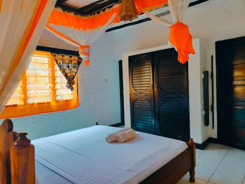 a bedroom with a bed with orange decorations on it at A three bedroom holiday home in Ukunda