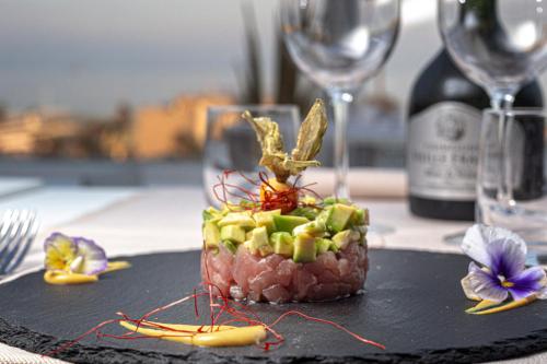 a piece of food on a black plate with wine glasses at Ambasciatori Suite Hotel in Sottomarina