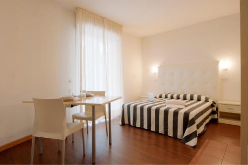 a bedroom with a bed and a table and a desk at Residence Marconi Mare in Rimini