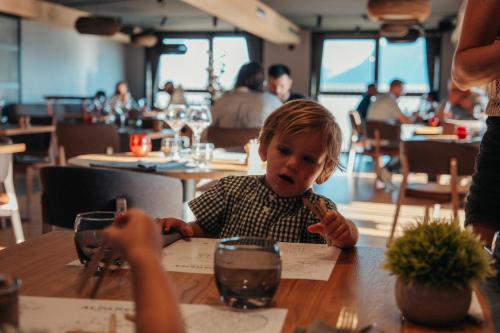 a young boy sitting at a table in a restaurant at Hôtel Alparena & Spa - 4 étoiles in La Rosière