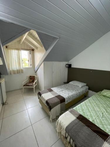 a attic bedroom with two beds and a chair at Break House Beach in Florianópolis