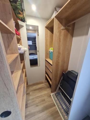 a walk in closet with wooden cabinets and a mirror at Mobil-home en camping proche de la mer in Ambon
