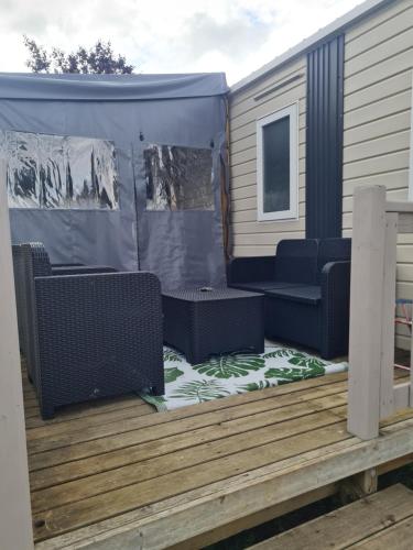 a covered deck with two chairs and a couch at Mobil-home en camping proche de la mer in Ambon