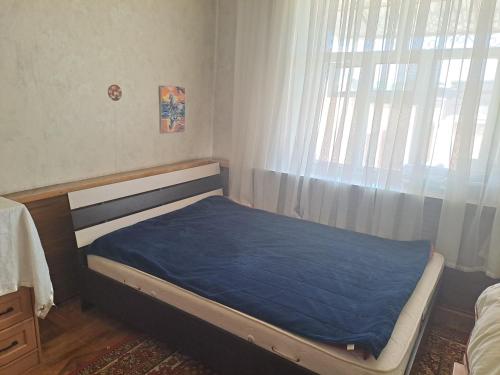 a bedroom with a bed with a blue blanket on it at Visit Balykchy in Balykchy