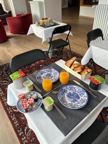 einen Tisch mit Teller mit Lebensmitteln und Tassen Orangensaft in der Unterkunft Domaine de Badine, 15 min Bordeaux & Saint-Emilion in Saint-Sulpice-et-Cameyrac