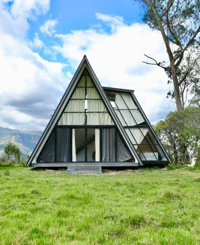 a frame house with a triangular roof on a field at Glamping Al Pie del Cerro in San Fernando