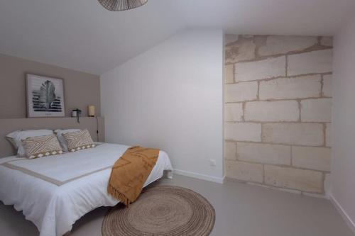 une chambre avec un lit et un mur de briques dans l'établissement Maison en pierre rénovée, à Les Artigues-de-Lussac