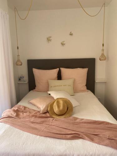 - un chapeau assis au-dessus d'un lit avec des oreillers dans l'établissement Dolce-Vita appart 3 étoiles, climatisé , 50M de la mer et aux portes de Menton ,parking gratuit, à Roquebrune-Cap-Martin