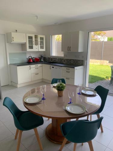 une cuisine avec une table et des chaises en bois et un plan de travail avec table et chaises dans l'établissement Maison 3 pièces - 2 chambres lits Queen Size avec wifi, à Grandchamp-des-Fontaines