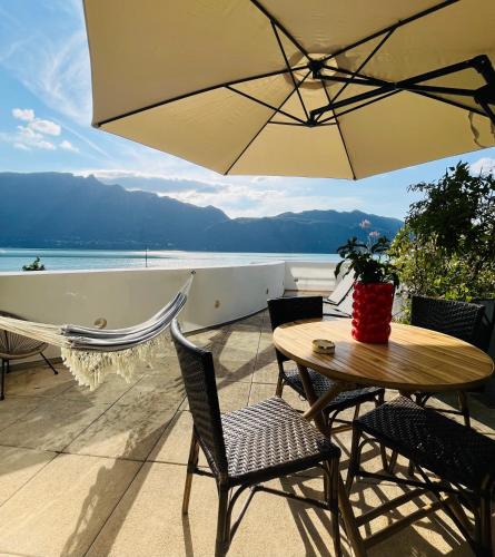 a table and chairs with an umbrella on a patio at Superbe Appartement avec vue sur le Lac du Bourget in Tresserves