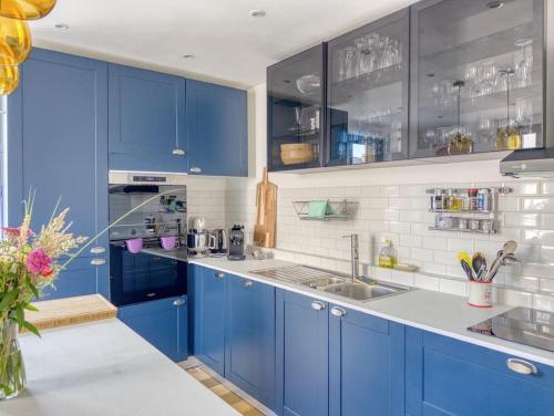 a blue kitchen with blue cabinets and a sink at Lampadaire du Martreuil Famille in Pierrefonds