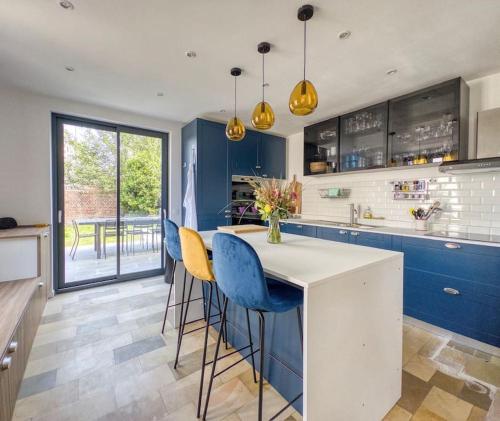 a kitchen with blue cabinets and blue bar stools at Lampadaire du Martreuil Famille in Pierrefonds