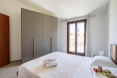a bedroom with a white bed with towels on it at Bernabé Apartment in Tortolì