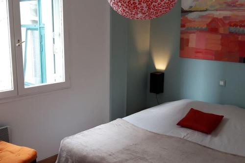 une chambre avec un lit avec un oreiller rouge dessus dans l'établissement Maisonnette l'Olivier Bleu, à Nantes