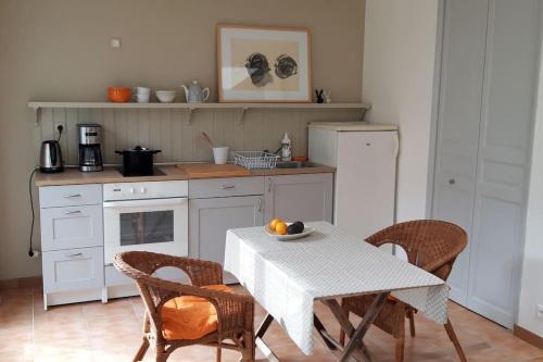 une cuisine avec une table et des chaises blanches et une table et une table et des chaises dans l'établissement Maisonnette l'Olivier Bleu, à Nantes