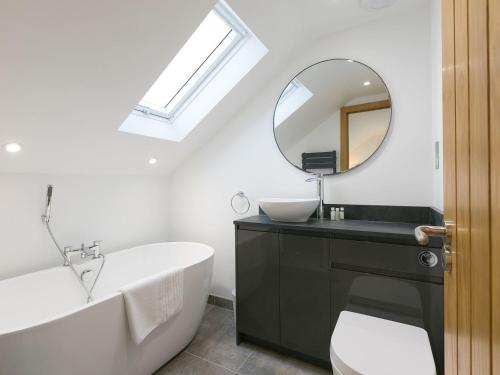 een badkamer met een bad, een wastafel en een spiegel bij Avon Cottage in St Ives