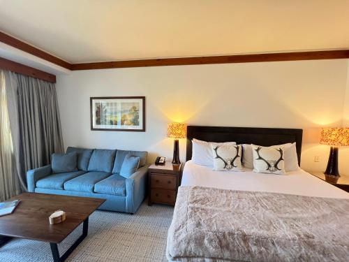 a bedroom with a bed and a blue couch at 1434 Lodge at Spruce Peak Ski in Ski out Studio Expansive Views By Stowe Mountain Rentals in Stowe