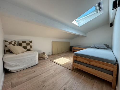 - une chambre mansardée avec 2 lits et une fenêtre dans l'établissement La maison du bonheur, à Mèze