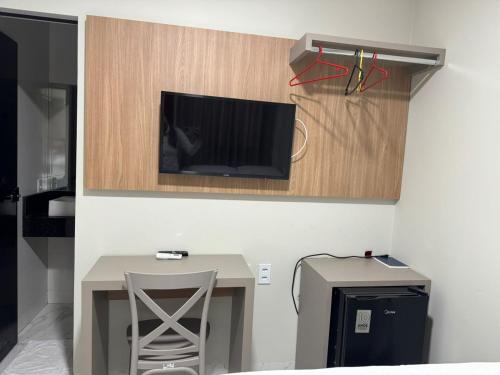 a room with a table and a tv on a wall at Hotel Radan in Luis Eduardo Magalhaes