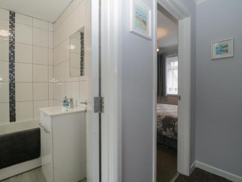 a bathroom with a sink and a tub and a bed at Flat 4, Big Tree Holiday Flats in Paignton