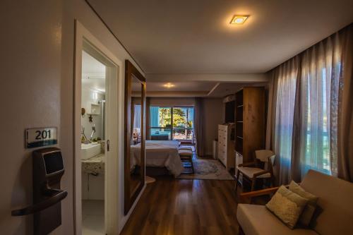 a hotel room with a bedroom and a bed and a window at Hotel VillaReal Guaratuba - Caieiras in Guaratuba