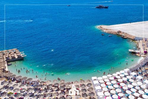 a beach with umbrellas and people in the water at DREAM HOTEL SARANDA in Sarandë