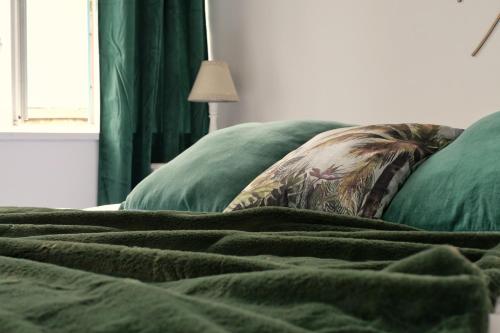 a bed with two green pillows and a blanket at Les chambres de l'Élysée in Pontrieux
