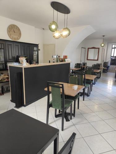 un restaurant avec des tables, des chaises et une horloge dans l'établissement Les chambres de l'Élysée, à Pontrieux
