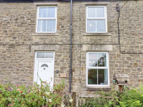a brick house with a white door and windows at Woodcutters Cottage in Haltwhistle