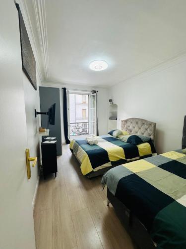 une chambre avec deux lits et une fenêtre dans l'établissement Appartement parisien, à Paris