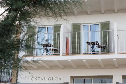 a white building with chairs on a balcony at Hostal Olga in Sant Antoni de Calonge