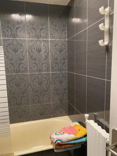 a bathroom with a tub and a tile wall at Appartement T3 dans résidence calme in Vizille