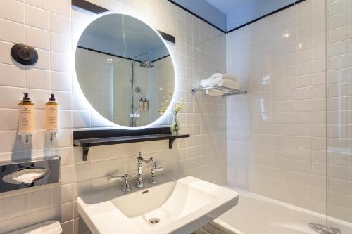 a white bathroom with a sink and a mirror at Hotel Plaza Biarritz Plage - Handwritten Collection in Biarritz