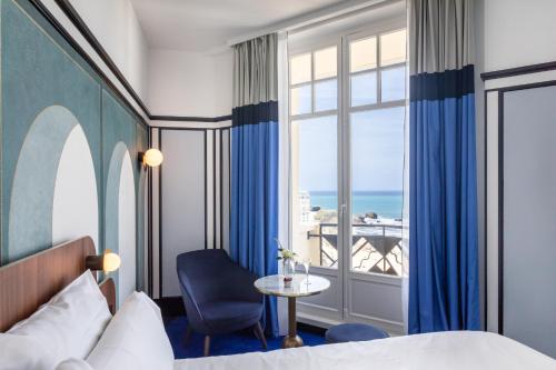 a hotel room with a bed and a table and a window at Hotel Plaza Biarritz Plage - Handwritten Collection in Biarritz